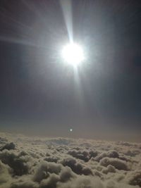 Low angle view of sun shining through clouds