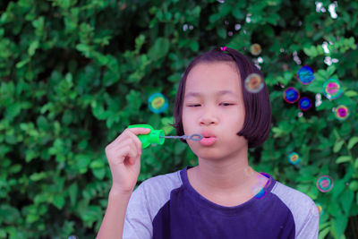 Girl blowing bubbles against plants