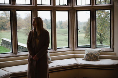 Rear view of woman looking through window