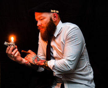 Man igniting cigarette against black background