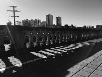 Bridge over river by buildings against clear sky