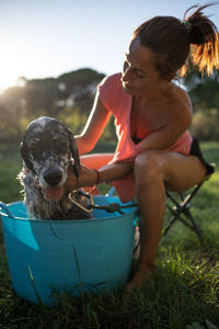 Side view of young woman with dog on grassy field