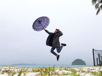 Man jumping in sea against sky