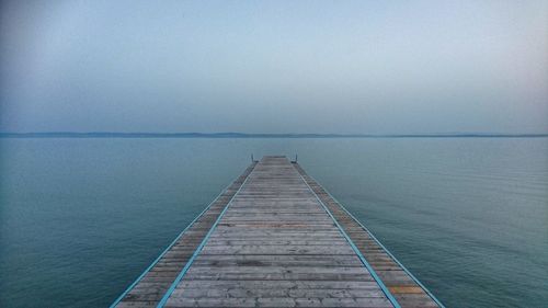Wooden pier over lake against clear sky