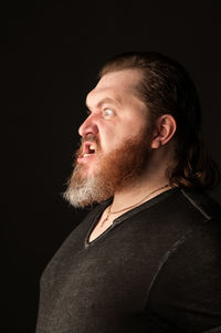 Portrait of man looking away against black background