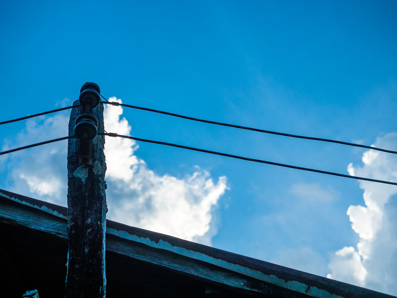 LOW ANGLE VIEW OF POWER CABLES AGAINST BLUE SKY