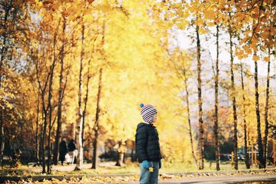 Boy wearing warm clothing while standing against trees during autumn