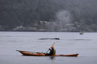 Man in boat on lake against sky