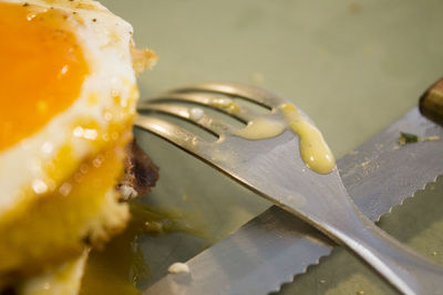 Close up of fried egg with fork and table knife on table