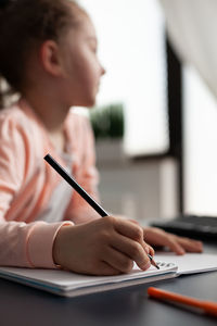 Young woman writing in book at table