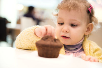 Cute baby girl eating cupcake at home