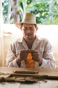 Man wearing hat holding leaf