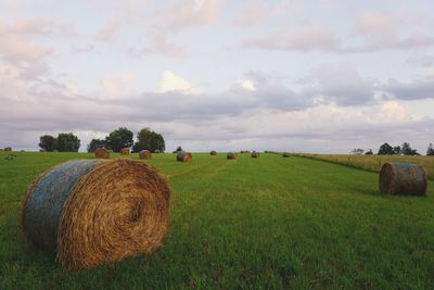 Hay bales on field against sky