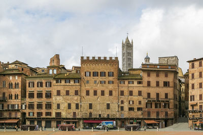 Buildings in city against cloudy sky