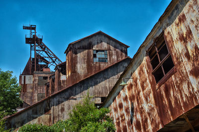 Low angle view of abandoned building against clear blue sky