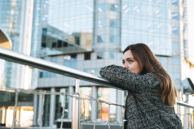 Portrait of young woman standing against buildings