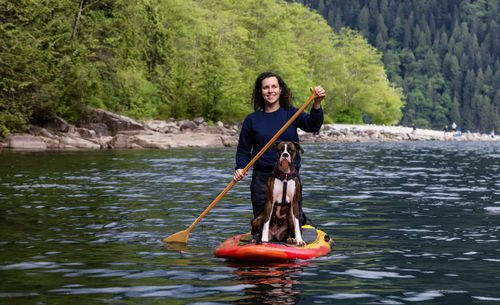 Portrait of smiling man holding boat in lake