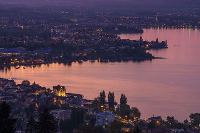 High angle view of illuminated buildings by river against sky at night
