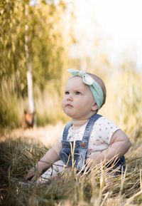 Cute baby girl sitting on grassy field