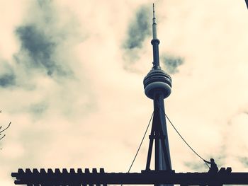 Low angle view of communications tower against cloudy sky