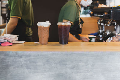 Iced coffee top of counter with barista working in background in cafe