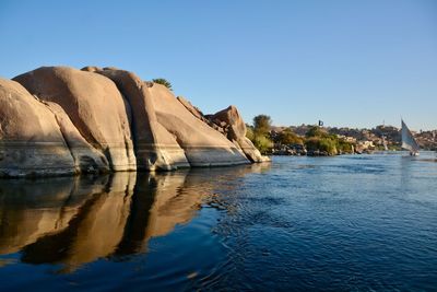 Rock formation in lake against clear blue sky