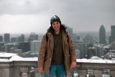 Portrait of smiling man standing against cityscape during winter