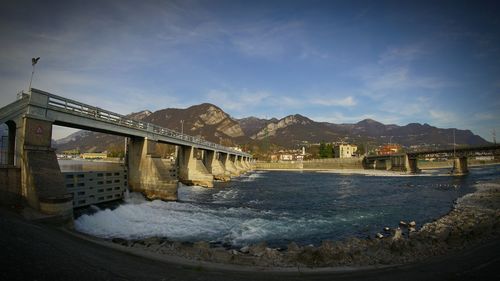 Bridge over river against cloudy sky