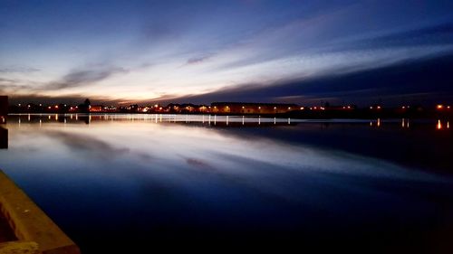 Swimming pool by lake against sky at night