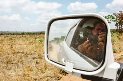 Reflection of man on side-view mirror