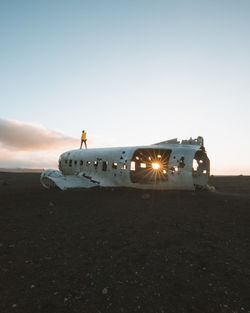 Abandoned airplane at beach against sky