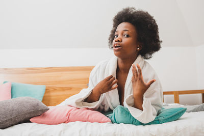 Portrait of smiling woman sitting on bed at home