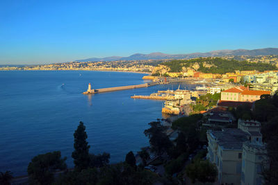 High angle view of city by sea against clear blue sky