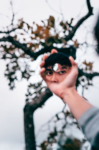 Cropped hand holding mirror with reflecting on face