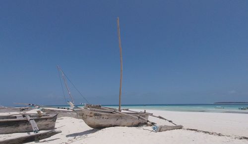 Sailboats on beach against clear blue sky