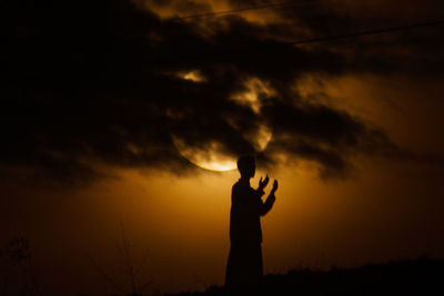 Silhouette man standing against dramatic sky during sunset