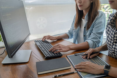 Midsection of woman using mobile phone while sitting on table