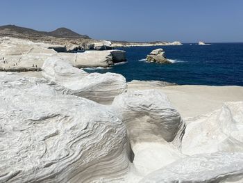 Rocks by sea against clear sky