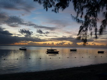 Boats in sea at sunset