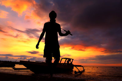 Silhouette of people on beach at sunset