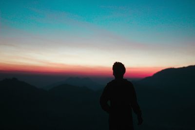 Silhouette man looking at mountain against sky during sunset