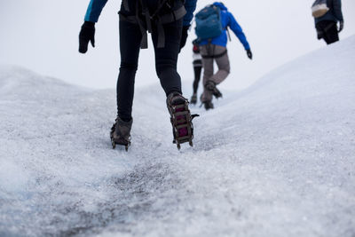 Cropped image of woman skating with friends on ice field