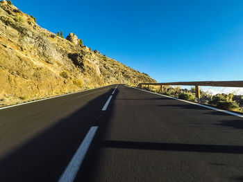 Empty road against clear blue sky