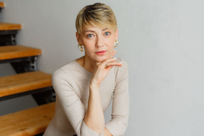 Portrait of young woman standing against wall