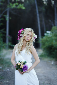 Beautiful woman with pink flower standing against blurred background