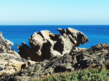 Rocks on shore by sea against sky