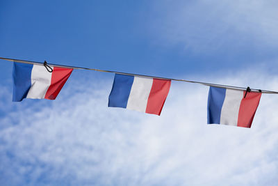 Low angle view of flags against blue sky