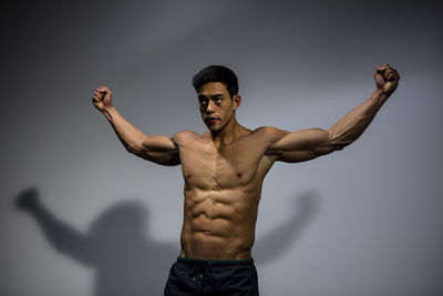 Shirtless muscular man standing against gray background