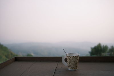 Close-up of coffee cup on table against sky