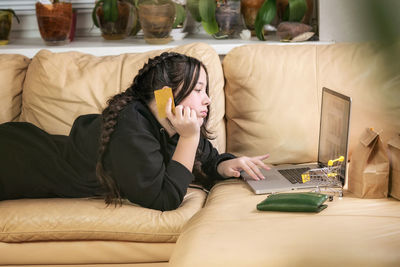 Young woman using mobile phone while sitting on sofa